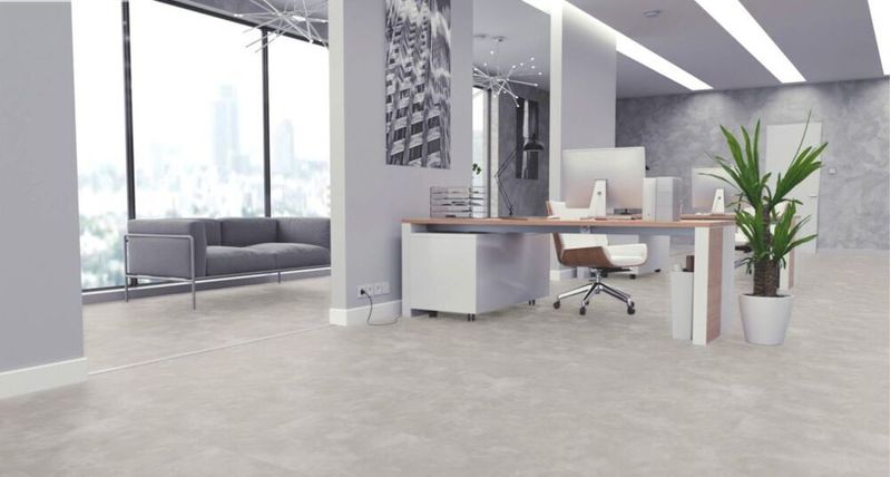 Piso Cerâmico Cementado aplicado em escritório de conceito aberto com escrivaninha, computador, ao fundo sofá e cortina de vidro